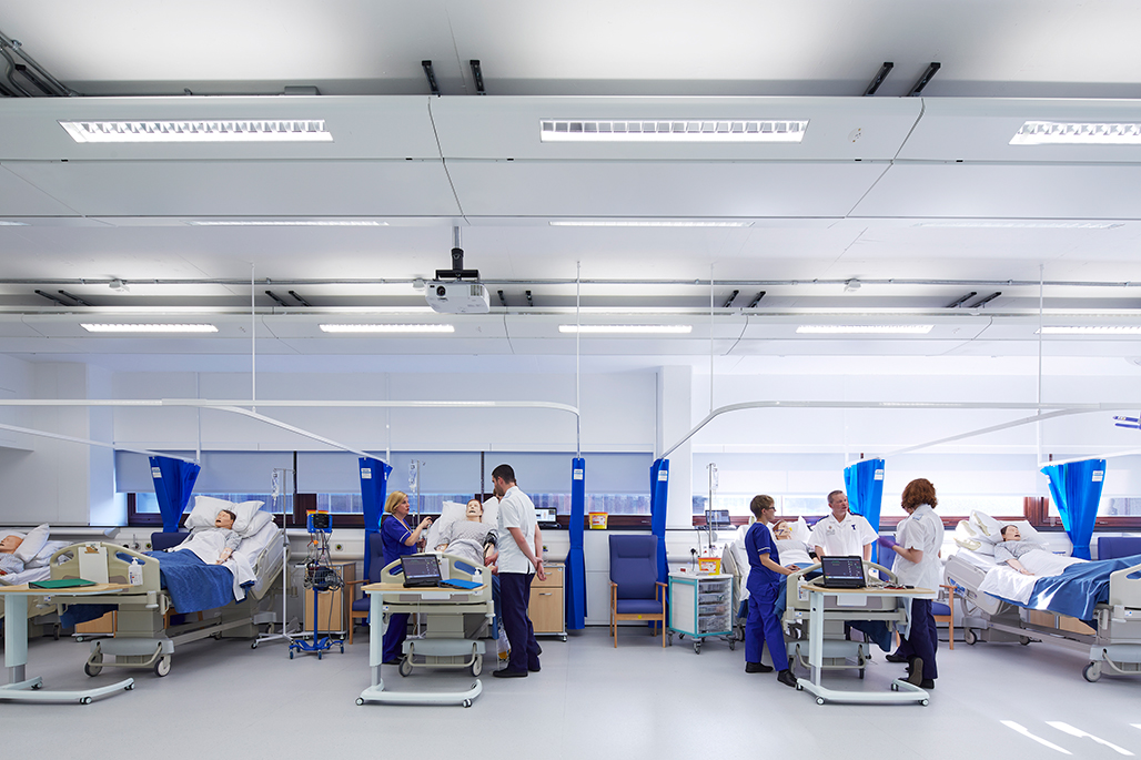 Students tending to a simulation manikin in a hospital bed